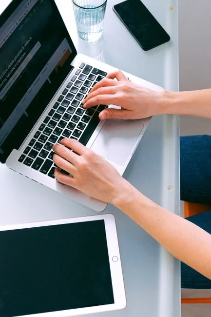 Close-up of hands interacting with a shopping website on a laptop screen indoors.